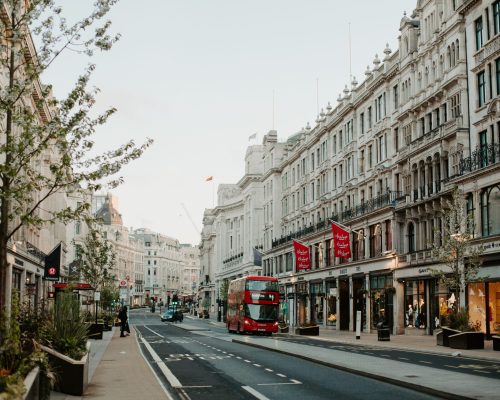 Bild med utsikt över en klassisk gata i London, en röd Londonbuss kör förbi